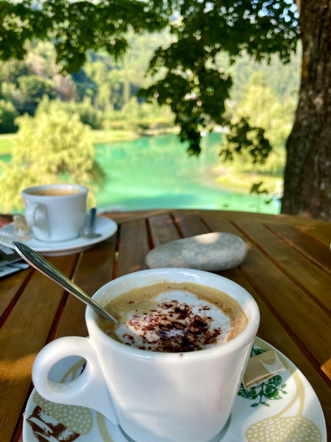 Deux cafés sur une table en bois au bord d’une eau turquoise
